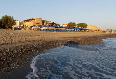 a sandy beach with a group of umbrellas at Indigo Mare in Plataniás