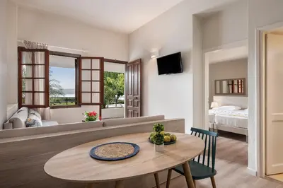 a living room with a table and a bedroom at Alianthos Suites in Tersanas