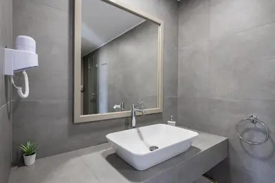 a bathroom with a white sink and a mirror at Alianthos Suites in Tersanas