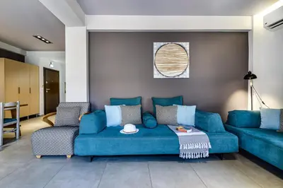 a living room with a blue couch and two chairs at City Breeze Apartment in Chania Town