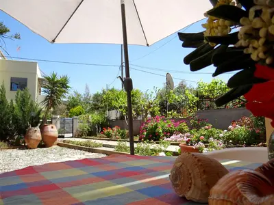 a table with an umbrella in a garden with flowers at Apartment by the Sea in Kato Daratso