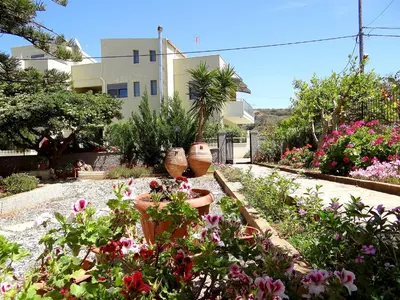 a garden with flowers and potted plants in front of a building at Apartment by the Sea in Kato Daratso