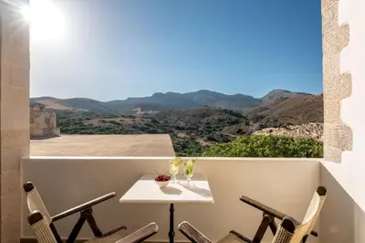 a table and chairs on a balcony with a view at Villa Aerino in Azoyirás