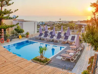 a pool with lounge chairs and a view of the ocean at Aphea Village in Kolymvari
