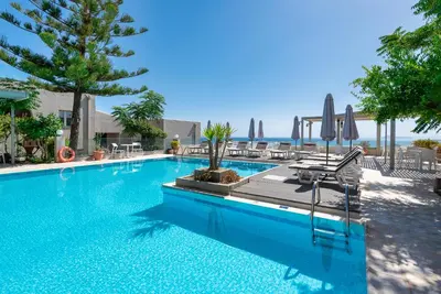 a swimming pool with chairs and umbrellas at Aphea Village in Kolymvari