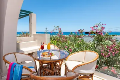 a table and chairs on a balcony with a view of the ocean at Aphea Village in Kolymvari