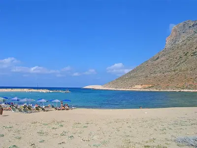 a beach with umbrellas and people sitting on the sand at The Well in Chorafakia
