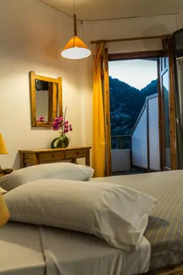 a bedroom with two beds and a mirror and a window at Neos Omalos Hotel in Omalós