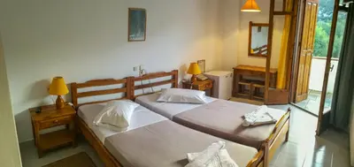 two beds in a room with two lamps and a mirror at Neos Omalos Hotel in Omalós