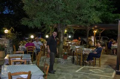 a man standing under a tree in a restaurant at Neos Omalos Hotel in Omalós