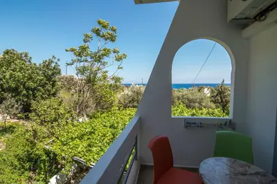 a room with a balcony with a view of the ocean at Megim Hotel in Palaiochóra