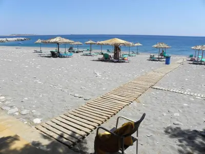 a sandy beach with chairs and umbrellas and the ocean at Megim Hotel in Palaiochóra