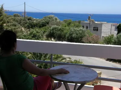 a woman sitting at a table on a balcony at Megim Hotel in Palaiochóra