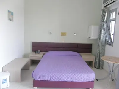a bedroom with a purple bed and a table at Megim Hotel in Palaiochóra