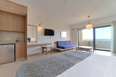 a bedroom with a large bed and a blue chair at Silver Beach Hotel & Apartments in Gerani Chanion
