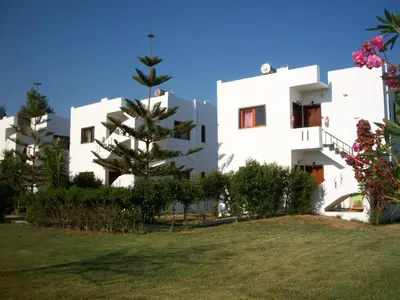 a white building with a tree in front of it at San Antonio Apartments in Kolymvari
