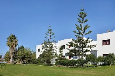 two trees in front of a white building at San Antonio Apartments in Kolymvari