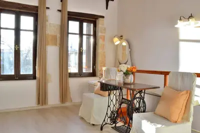a living room with a table and chairs and windows at Charming stone corner house in Chania Town