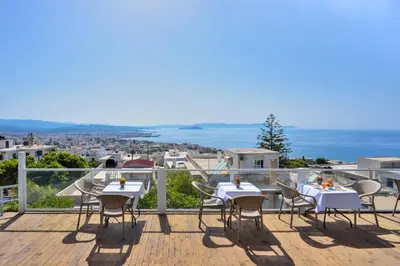a balcony with tables and chairs and the ocean at Loucerna Suites Chania in Chania Town