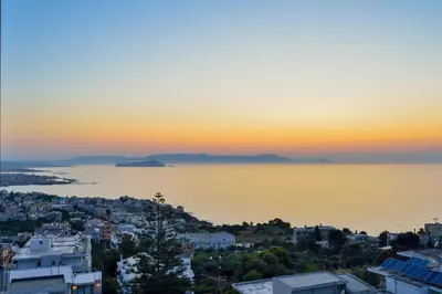 a view of a city and the ocean at sunset at Loucerna Suites Chania in Chania Town