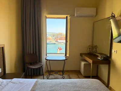 a bedroom with a window with a view of the water at Helena Hotel in Chania Town