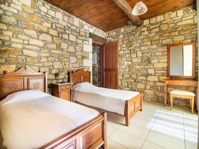 a bedroom with two beds and a stone wall at Falasarna Villas in Falasarna