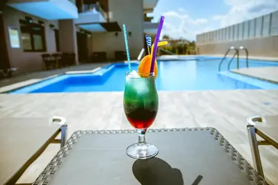 a drink sitting on a table next to a pool at Gregory Comfort Hotel in Kalamaki Chanion
