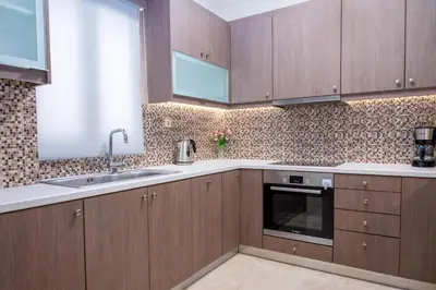 a kitchen with wooden cabinets and a sink at Barbaras Apartments in Kato Daratso