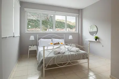 a white bedroom with a bed and a window at Angel-kolymvari4you in Kolymvari