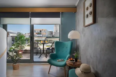 a living room with a blue chair and a balcony at Nidus Villa in Souda