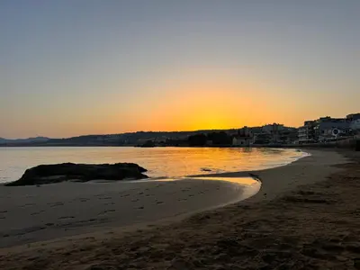 a beach with the sun setting in the distance at Mare suites 1 in Chania Town