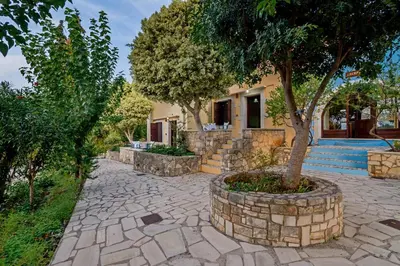 a stone walkway with a tree in front of a house at Heliopetra studios, small village close to beaches in Koprána