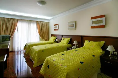 two beds in a hotel room with yellow sheets at Porto Alegre Hotel in Kalamaki Chanion