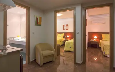 a room with two beds and a bathroom with a sink at Porto Alegre Hotel in Kalamaki Chanion