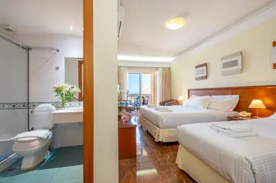 a hotel room with two beds and a bathroom at Porto Alegre Hotel in Kalamaki Chanion
