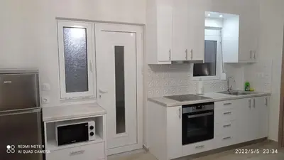 a kitchen with white cabinets and a sink and a microwave at Sunshine Apartments in Kato Daratso