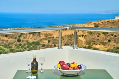 a bowl of fruit on a table with a bottle and glasses at Achilleas Apartments with Sea View in Kolymvari