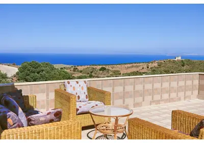a patio with wicker chairs and a table and the ocean at Achilleas Apartments with Sea View in Kolymvari