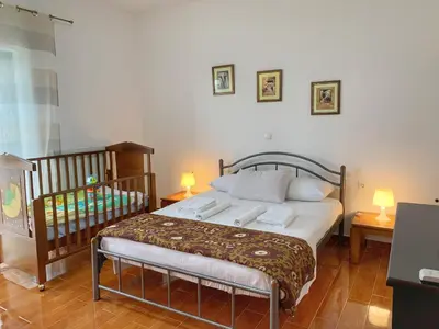 a bedroom with a bed and a crib with two lamps at Evaggelias Home Gavalochori in Gavalochori