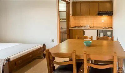a small kitchen with a wooden table and a bed at Merabello Apartments in Agia Marina Nea Kydonias