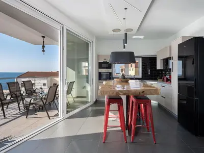 a kitchen with a wooden table with red stools at View Point Apartment in Chania Town