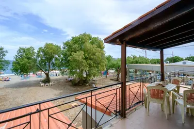 a balcony with a table and chairs and a beach at Seafront Paradise steps to Beach in Plataniás