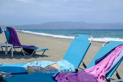 two beach chairs and towels on the beach at Seafront Paradise steps to Beach in Plataniás