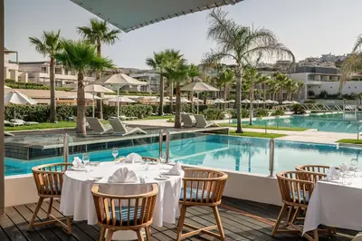 a restaurant with a pool and tables and chairs at Avra Imperial Hotel in Kolymvari
