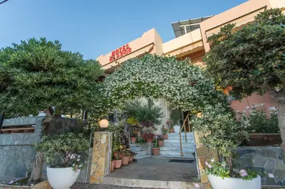 a building with trees and flowers in front of it at Glaros Hotel in Palaiochóra