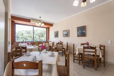 a dining room with tables and chairs and a window at Glaros Hotel in Palaiochóra