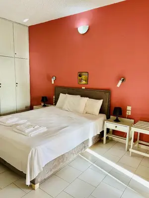 a bedroom with a large bed with a red wall at Terpsichori villa and apartments in Kalamaki Chanion