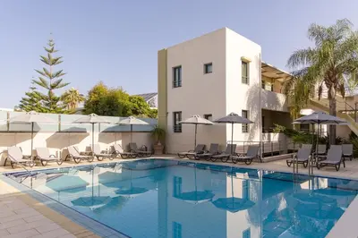 a pool with chairs and umbrellas next to a building at Athina Beach Hotel in Kato Daratso