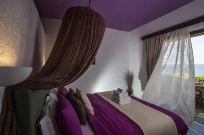 a bedroom with a bed with purple walls and a window at Villa Georgia Apartments & Suites in Kalamaki Chanion