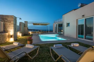 a backyard with a swimming pool and two lounge chairs at Pantanassa Villa Thalia in Agia Marina Nea Kydonias